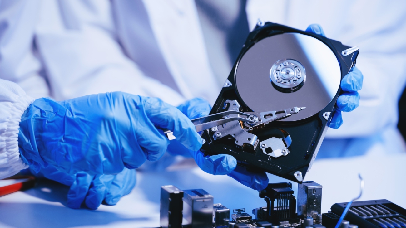 Mavi statik eldiven giyen teknisyen, elinde açık sabit disk tutarak veri kurtarma işlemi yapıyor