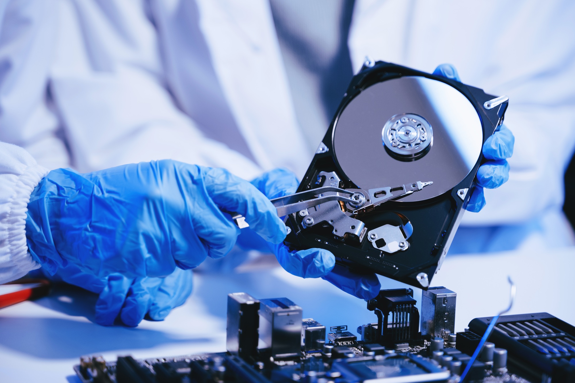 Mavi statik eldiven giyen teknisyen, elinde açık sabit disk tutarak veri kurtarma işlemi yapıyor